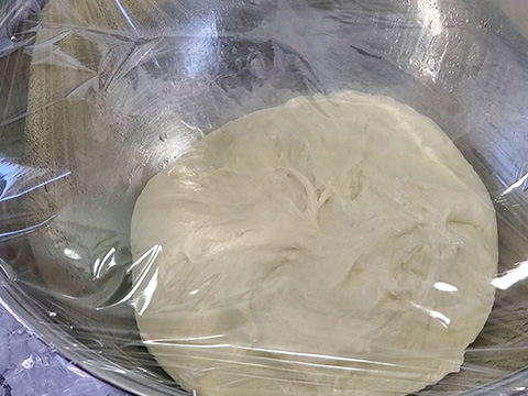 Covering large bowl with dough inside with plastic wrap
