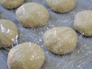 Covering shaped dough with plastic wrap