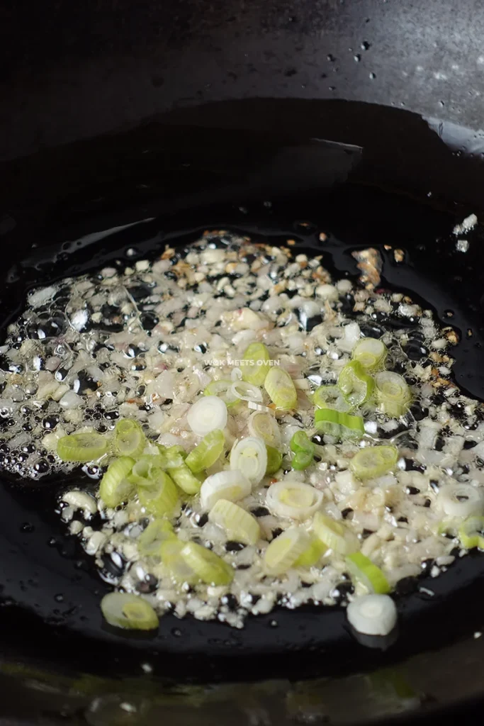 Adding in green onions to wok