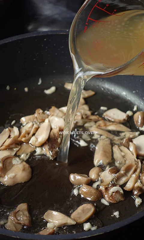 adding in chicken stock to wok