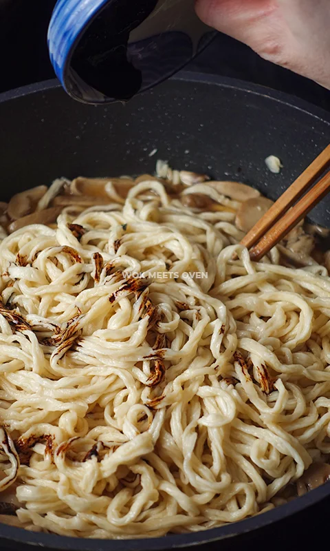 adding in dark soy sauce to noodles