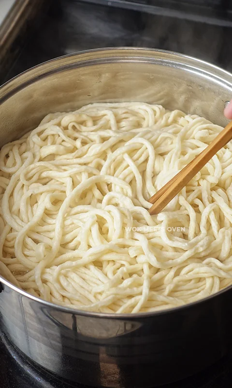 using chopsticks to separate e-fu noodles in pot
