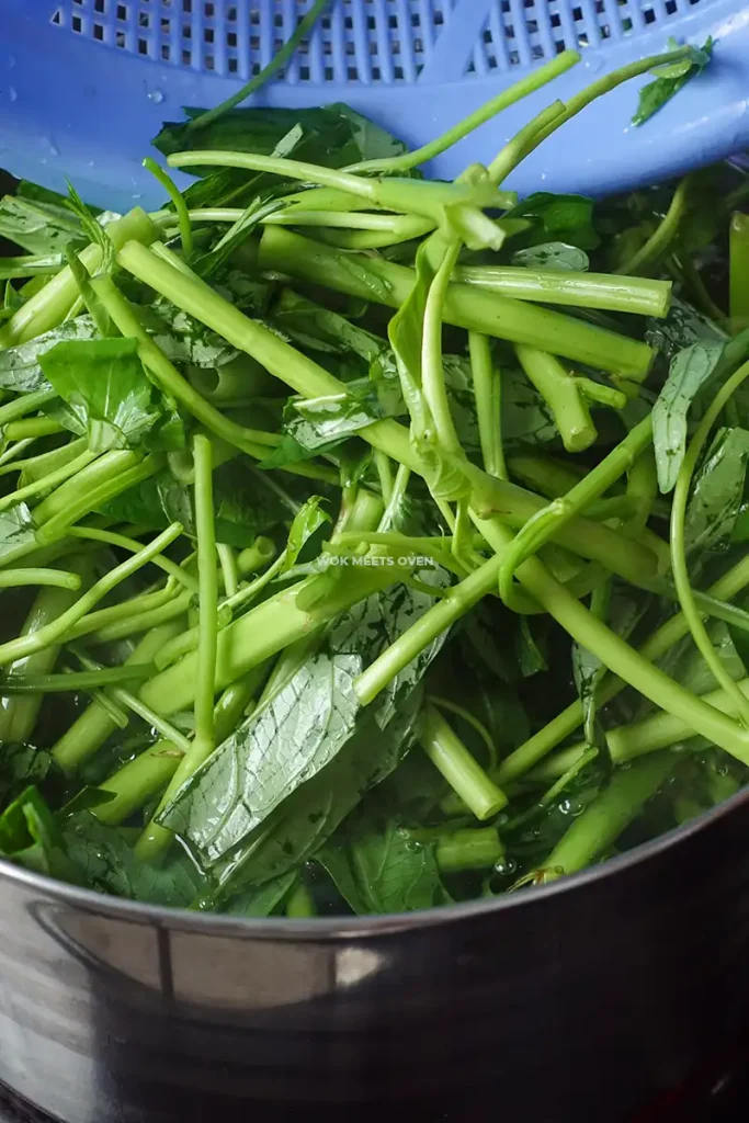 Adding water spinach to pot of hot water