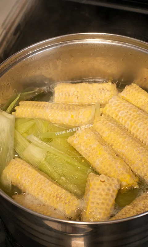 corn cobs, husks, and silk simmering inside of pot