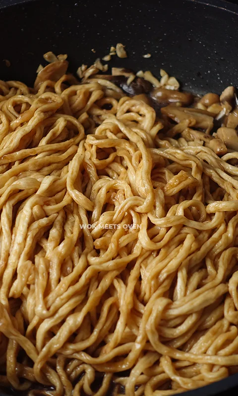 mixing dark soy sauce with noodles