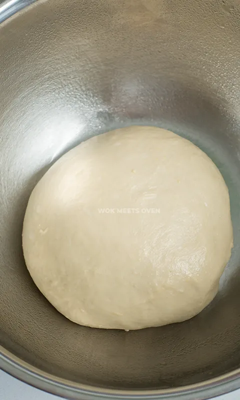 Dough shaped into round ball inside of bowl