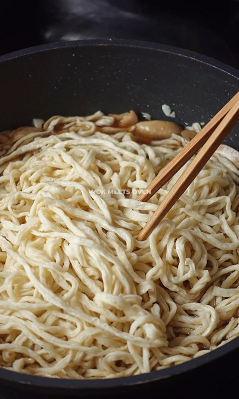mixing noodles in wok
