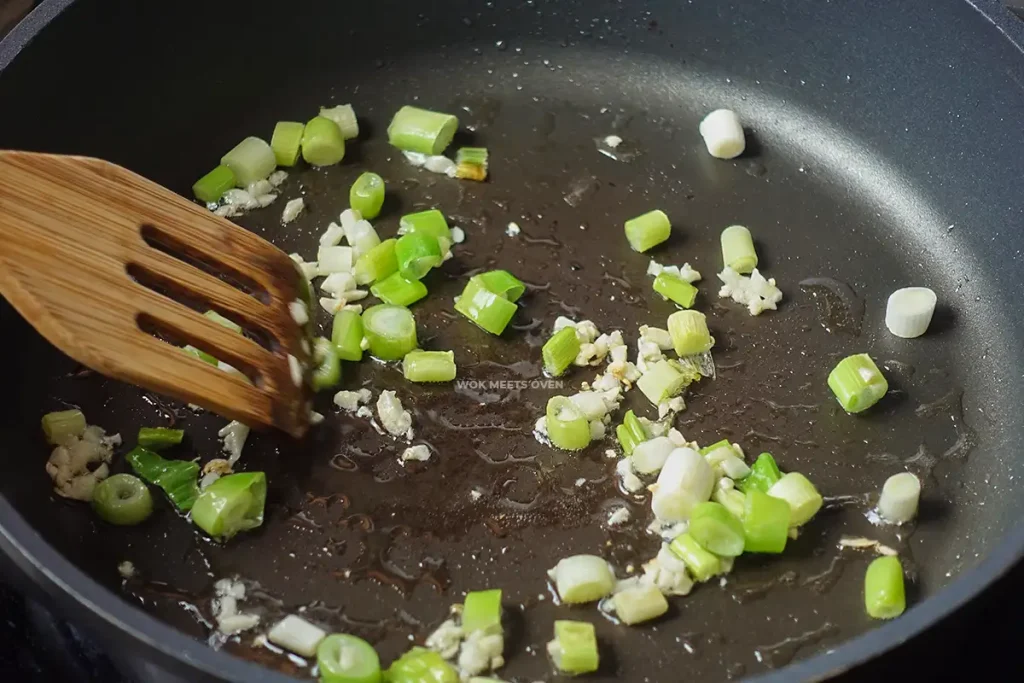 stir-frying green onions and minced garlic on wok