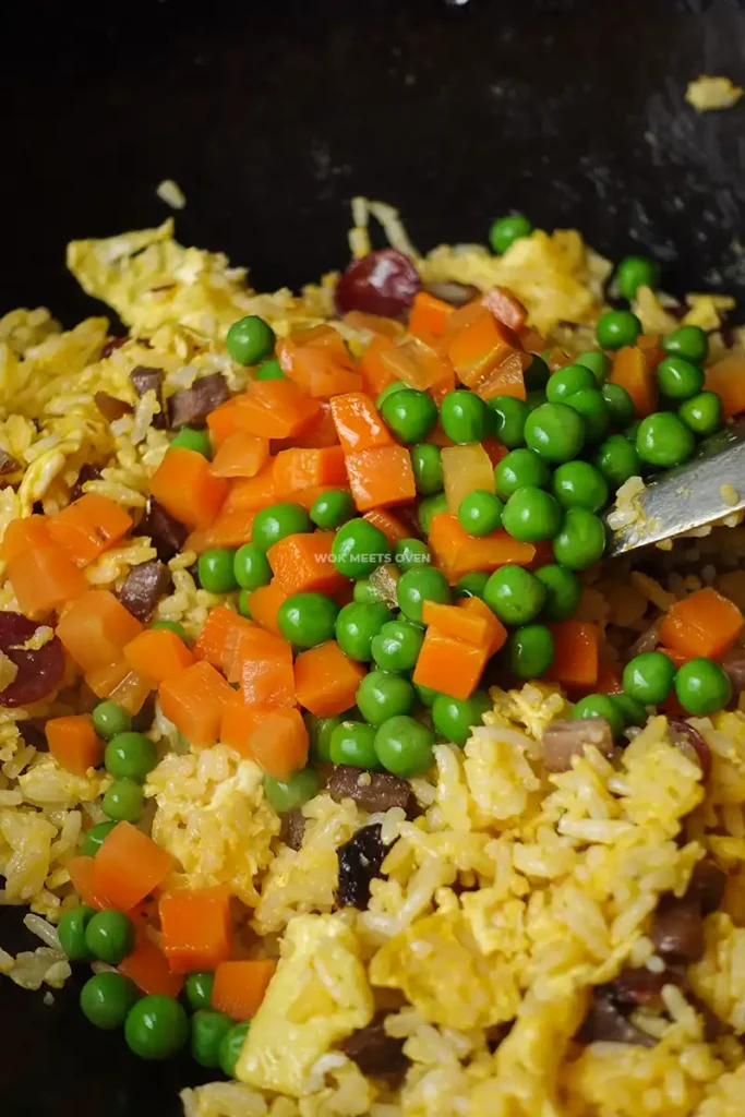 Adding in carrots and peas to fried rice