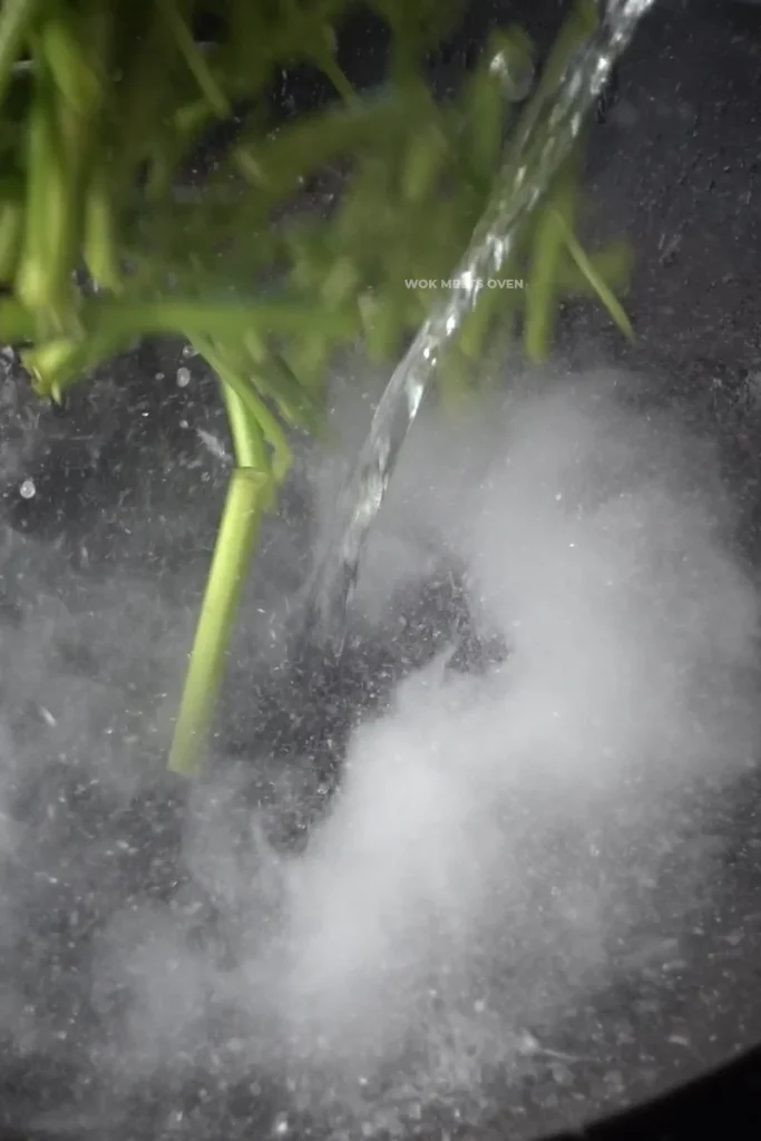 Adding water and water spinach to wok