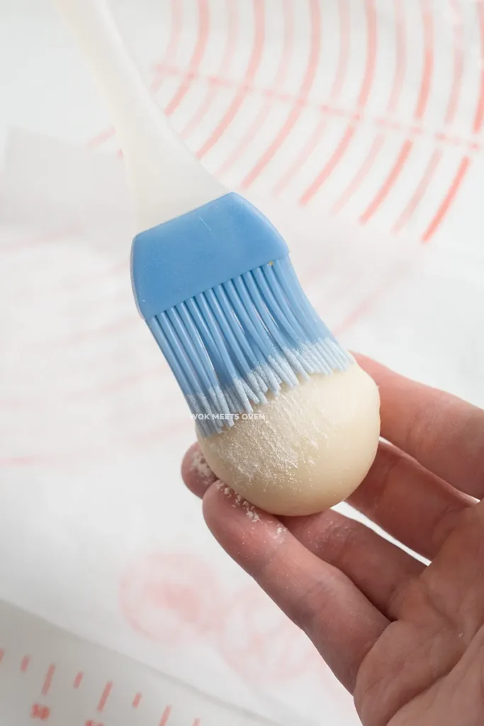 Brushing glutinous rice flour onto mooncake balls