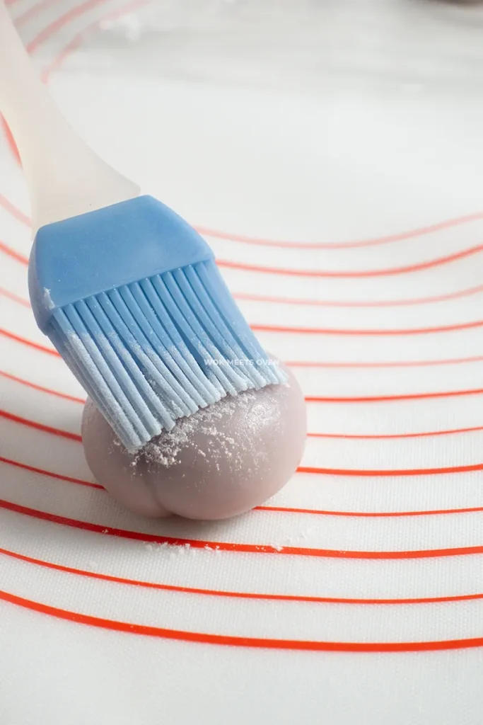 Brushing cooked glutinous rice flour onto snow skin mooncakes