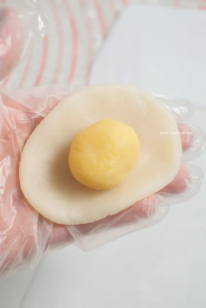 Putting custard filling in middle of flatten snow skin dough