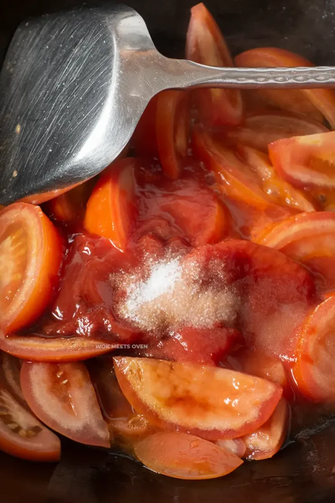 Adding in ketchup, sugar, salt, and soy sauce to tomatoes