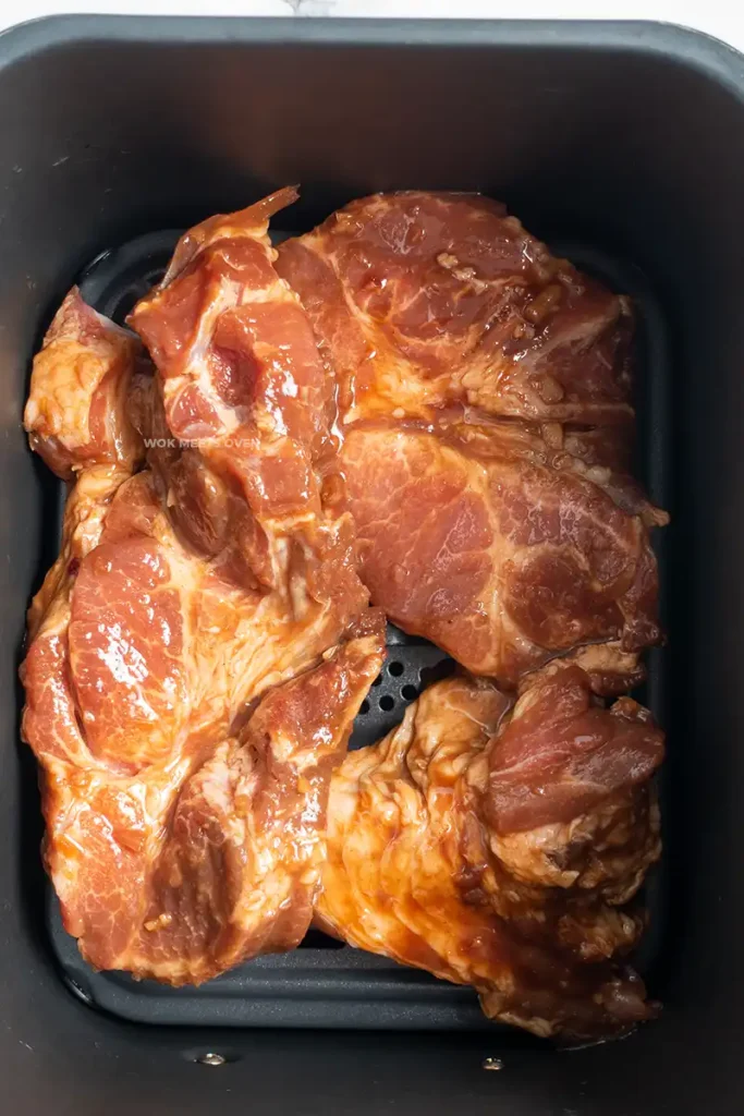 Placing pork shoulder inside of air fryer tray