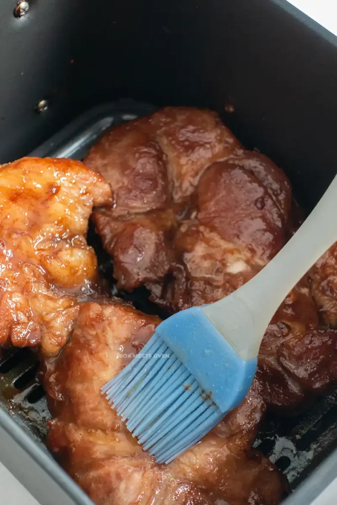 Brushing honey glaze onto pork shoulder