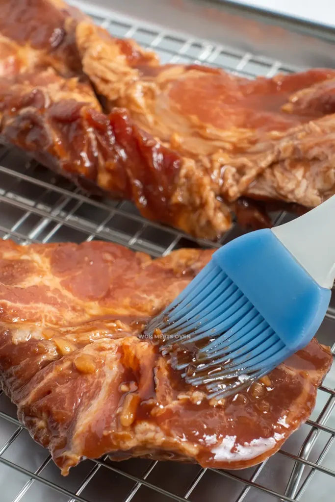 Brushing marinade onto char siu before roasting