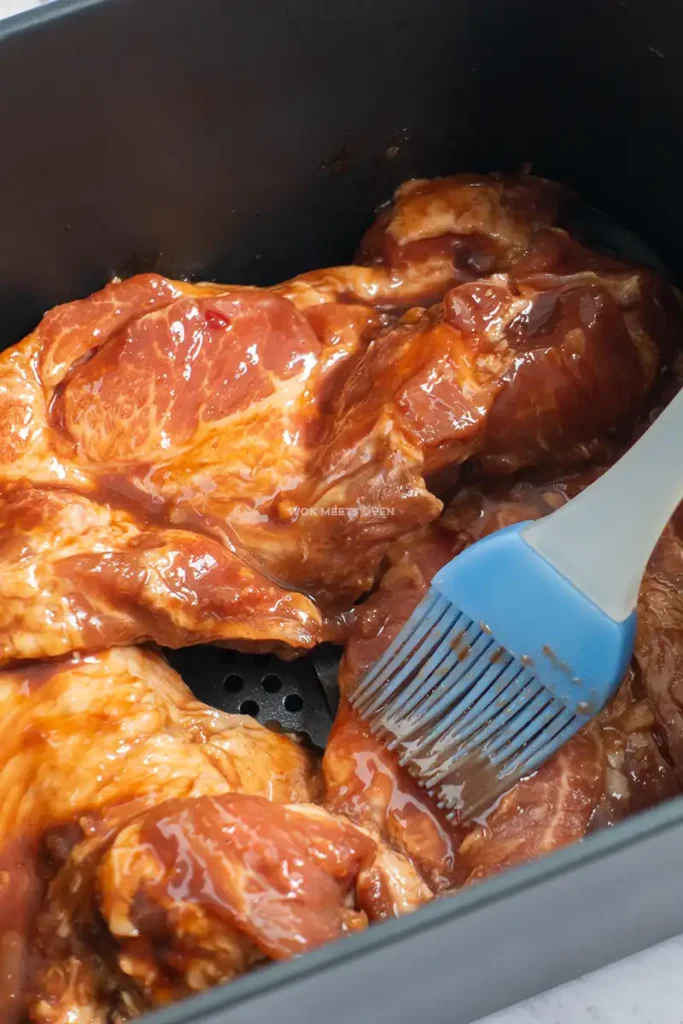 Brushing marinade onto pork shoulder