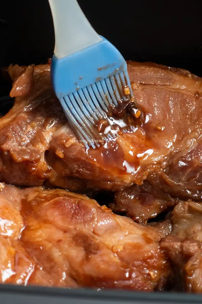 Brushing marinade again onto pork shoulder