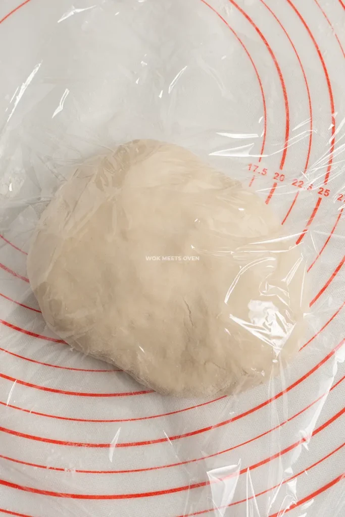 Covering dough with plastic wrap