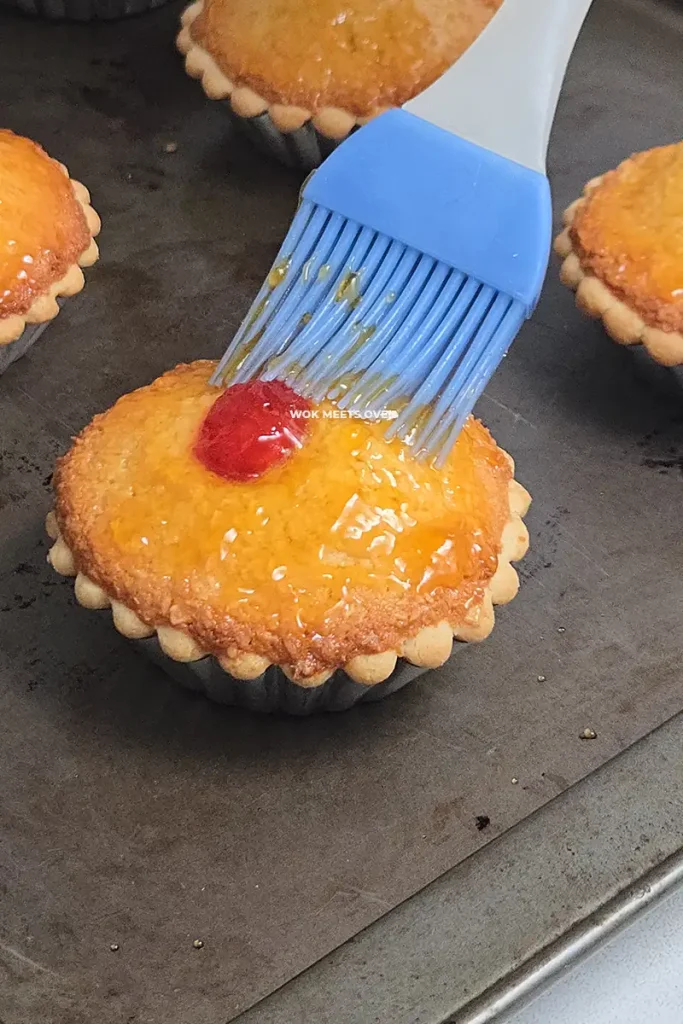 Brushing jam on top of coconut tarts